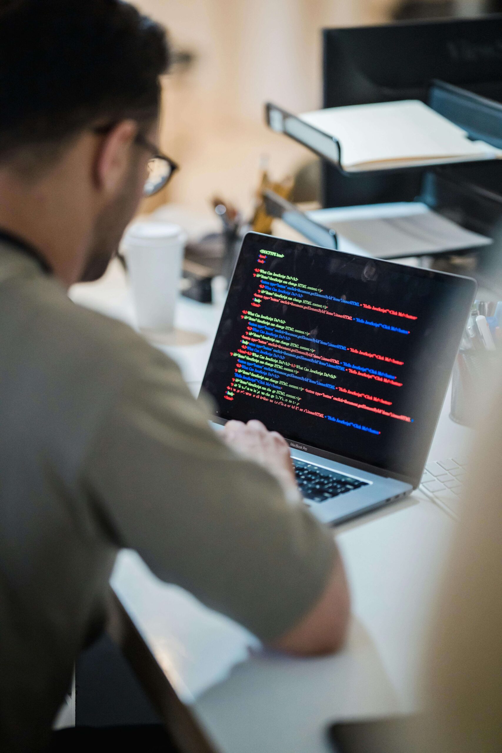 Focused programmer coding on a laptop in an office environment.